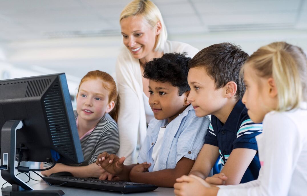 Group of students in front of computer with teacher